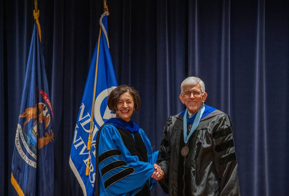 Provost Mili smiles and shakes hands with man